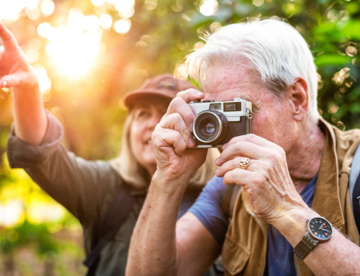 Senior trekker taking a photo with a film camera