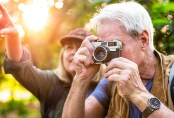 Senior trekker taking a photo with a film camera