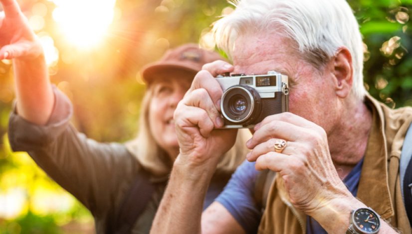 Senior trekker taking a photo with a film camera